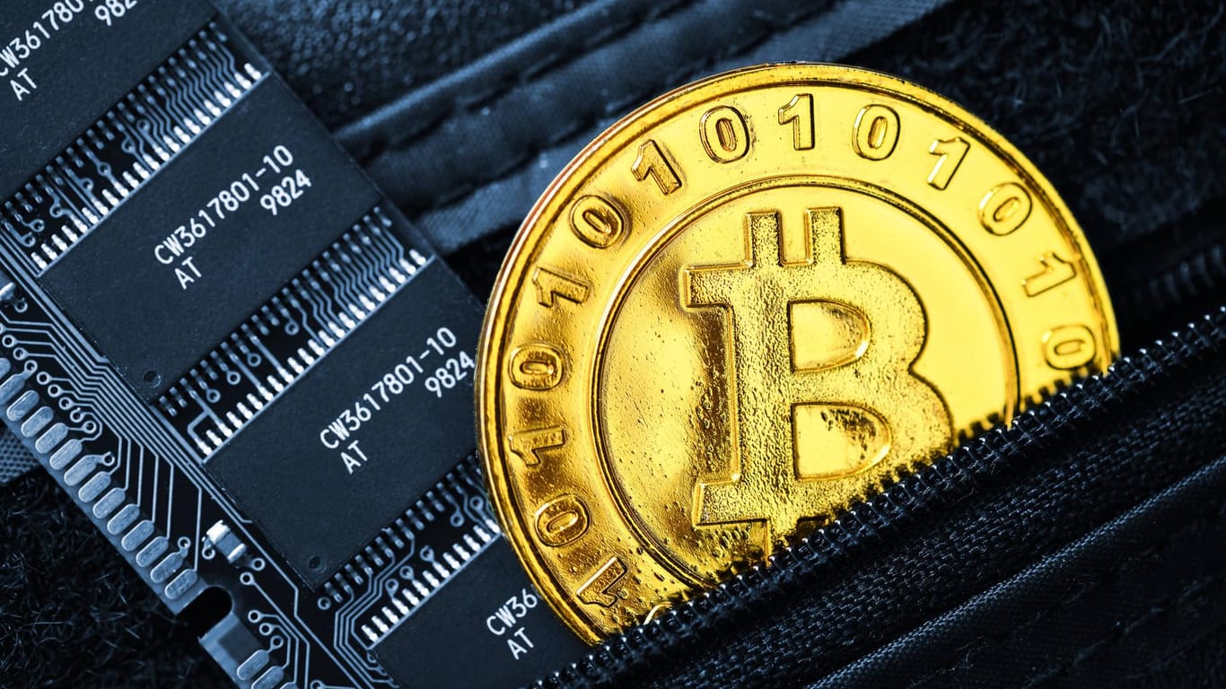 Münze mit Bitcoin Zeichen und Computerplatine in einem Portemonnaie: Ein 36-Jähriger wird beschuldigt, mehrere digitale Geldbörsen geplündert zu haben.