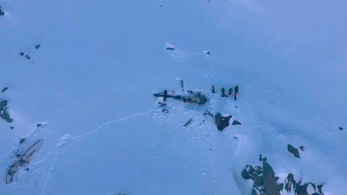 Eine Gruppe von Bergrettern steht neben den Trümmern des Hubschraubers, nachdem dieser mit einem Flugzeug kollidiert ist: Die beiden Maschinen sind im Aostatal in den italienischen Alpen abgestürzt.