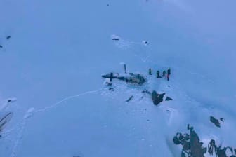Eine Gruppe von Bergrettern steht neben den Trümmern des Hubschraubers, nachdem dieser mit einem Flugzeug kollidiert ist: Die beiden Maschinen sind im Aostatal in den italienischen Alpen abgestürzt.