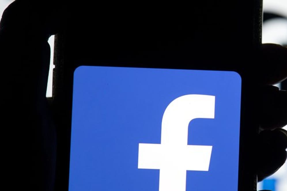 Das Facebook-Logo ist auf dem Display eines Mobiltelefon zu sehen.