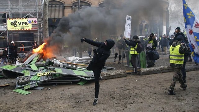 Ein Demonstrant in Paris bewirft die Polizei.