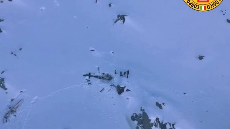 Dieses vom italienischen Bergrettungsdienst zur Verfügung gestellte Bild zeigt eine Gruppe von Bergrettern, die neben den Trümmern des Hubschraubers stehen.