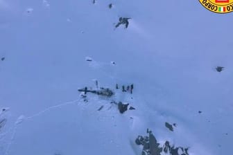 Dieses vom italienischen Bergrettungsdienst zur Verfügung gestellte Bild zeigt eine Gruppe von Bergrettern, die neben den Trümmern des Hubschraubers stehen.