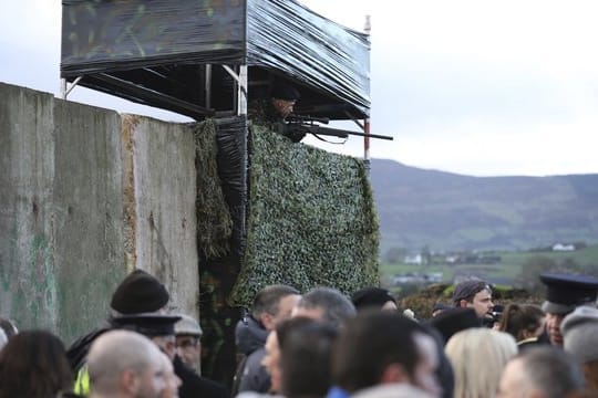 Ein als Soldat verkleideter Demonstrant steht auf einer Wachturm-Attrappe.