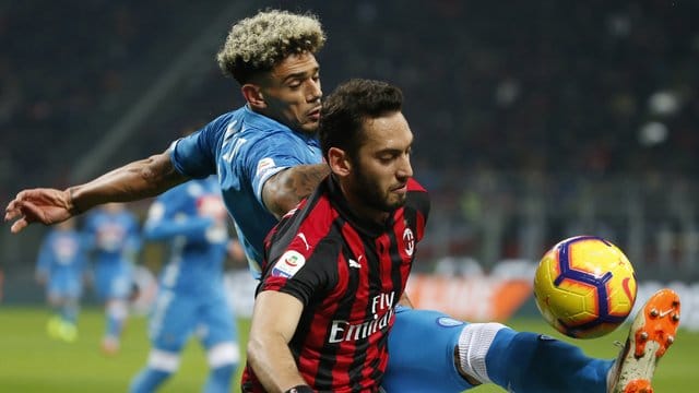 Kevin Malcuit (l) aus Neapel spitzelt Milan-Profi Hakan Calhanoglu den Ball weg.