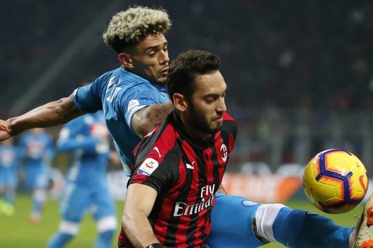 Kevin Malcuit (l) aus Neapel spitzelt Milan-Profi Hakan Calhanoglu den Ball weg.