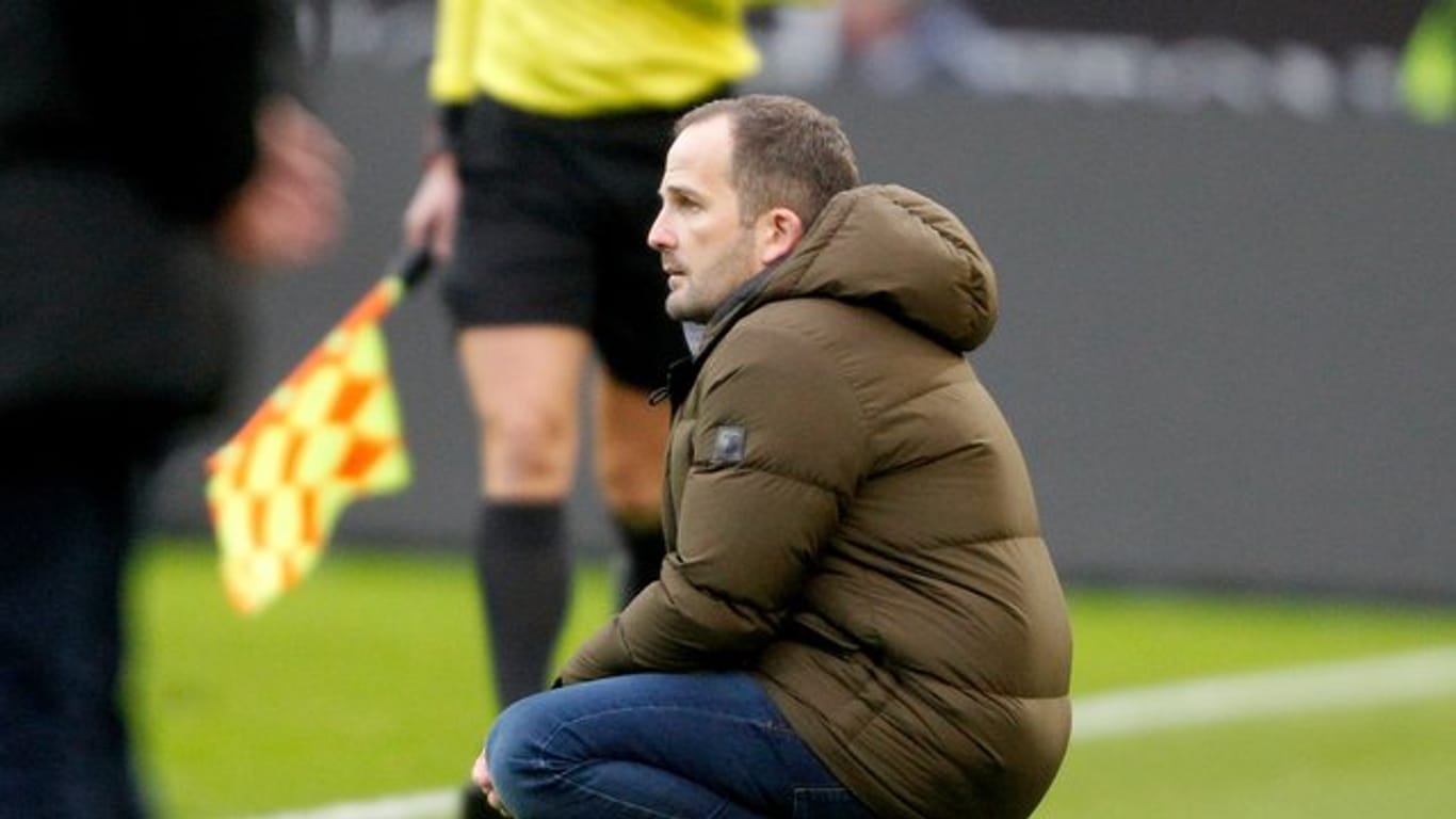 Augsburgs Trainer Manuel Baum hockt beim Spiel in Mönchengladbach an der Seitenlinie.