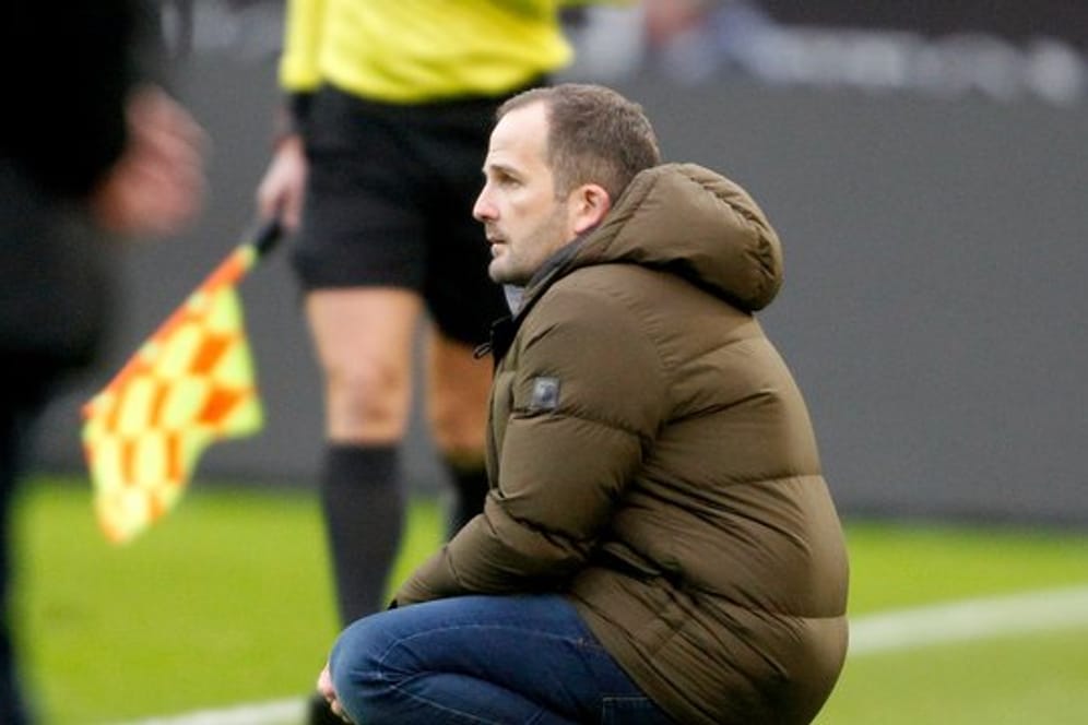 Augsburgs Trainer Manuel Baum hockt beim Spiel in Mönchengladbach an der Seitenlinie.