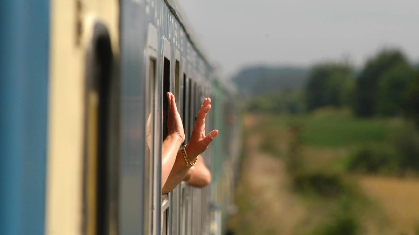 Hände schauen aus einem Zug: Aus Angst vor Taschendieben sperrt sich ein Mann auf einer Zugreise in seinem Abteil ein und kommt nicht mehr ohne Hilfe der Polizei wieder raus. (Symbolbild)