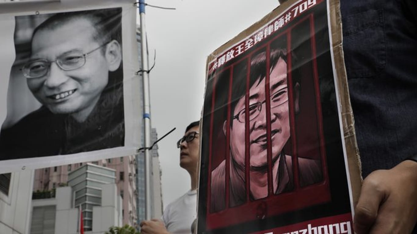 Demonstranten halten Plakate mit dem Bild des gestorbenen chinesischen Friedensnobelpreisträgers Liu Xiaobo (l) und des inhaftierten Menschenrechtlers Wang Quanzhang während einer Protestkundgebung im Juli 2018.