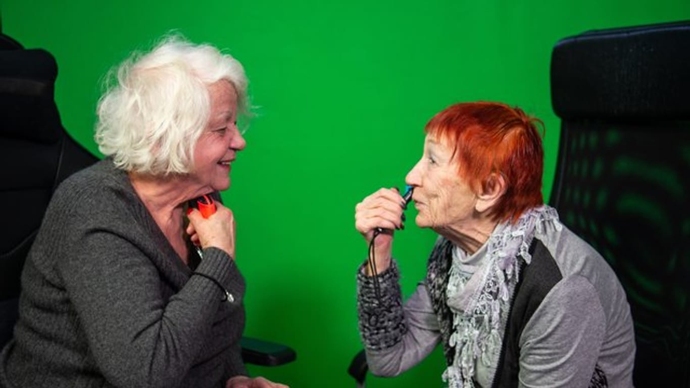 Evelyn Gundlach (r) und Ursula Cezanne (l) spielen in einem Berliner Studio an der Nintendo Switch ein Videospiel, bei dem man sich mit dem Controller rasieren muss.