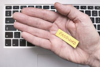 Eine Hand hält ein Notizzettel mit der Aufschrift "Password": Lange und komplizierte Kennwörter können in einem Passwortmanager gespeichert werden.