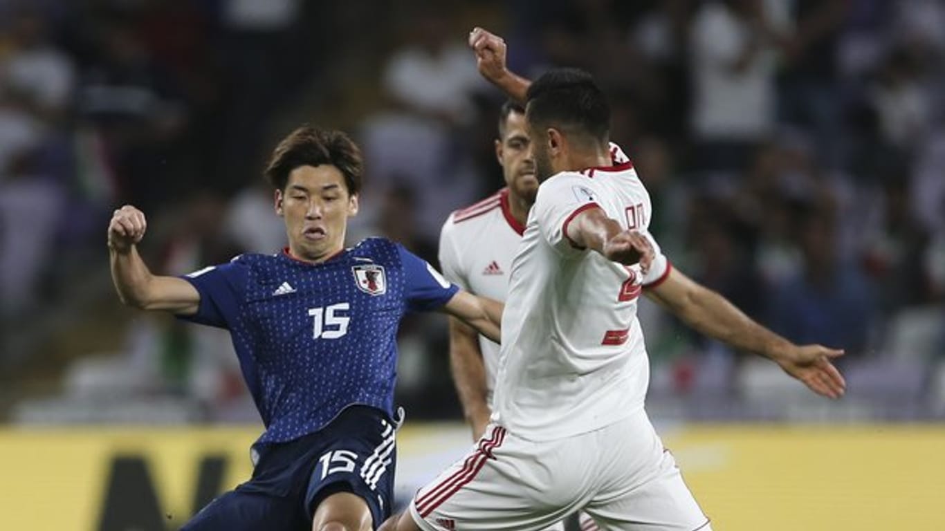 Irans Milad Mohammadi (r) kämpft gegen den Japaner Yuya Osako um den Ball.