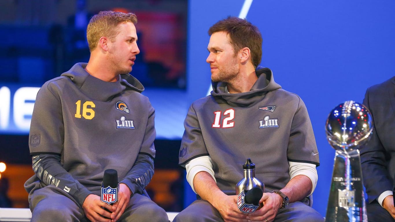 Die Quarterbacks Tom Brady (rechts, New England) und Jared Goff (Rams) sitzen neben der Vince Lombardy Trophy.