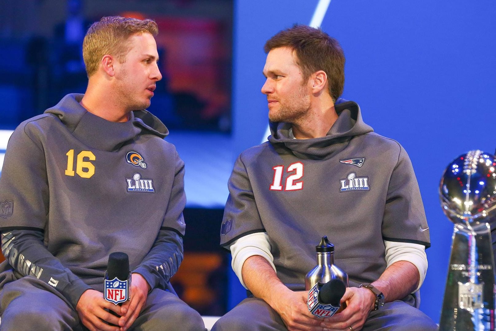 Die Quarterbacks Tom Brady (rechts, New England) und Jared Goff (Rams) sitzen neben der Vince Lombardy Trophy.