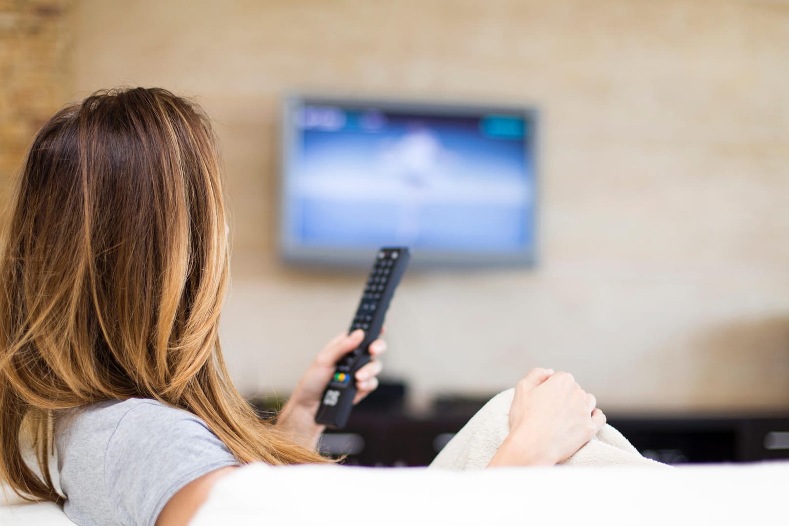 Eine Frau schaut Fernsehen (Symbolbild): Die Stiftung Warentest hat 21 Fernsehgeräte bis 43 Zoll Bildschirmdiagonale getestet.