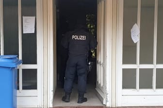 Polizist in einem Hauseingang in Meldorf: In dem Ort im Kreis Dithmarschen in Schleswig-Holstein haben BKA-Beamte drei Männer aus dem Irak festgenommen.