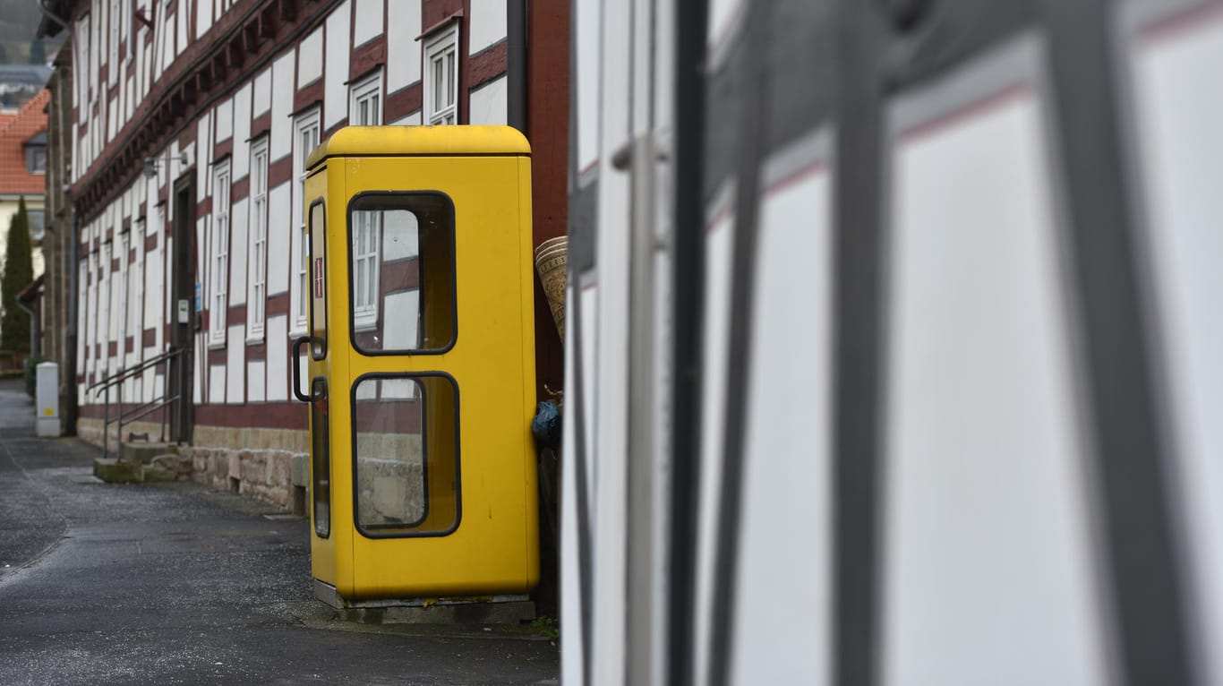 Eine gelbe Telefonzelle steht vor einem Fachwerkhaus: Vielerorts gehören die gelben Kabinen ins Stadtbildt – doch ob sie bleiben, hängt davon ab, ob sie genutzt werden.