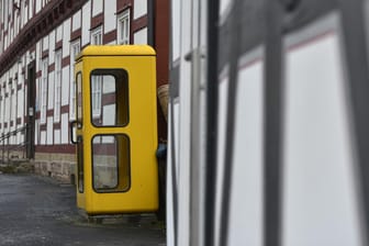 Eine gelbe Telefonzelle steht vor einem Fachwerkhaus: Vielerorts gehören die gelben Kabinen ins Stadtbildt – doch ob sie bleiben, hängt davon ab, ob sie genutzt werden.