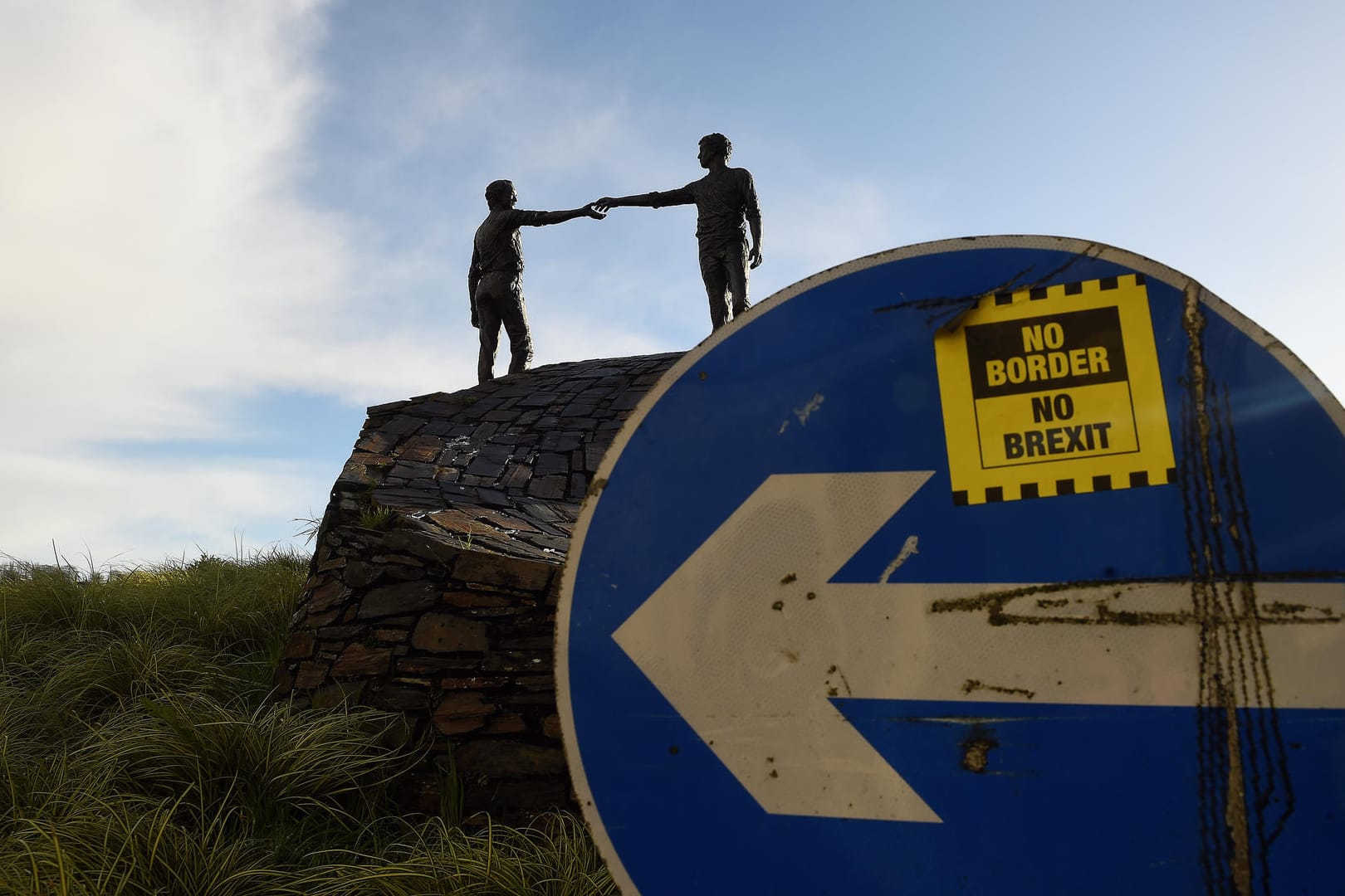 Verkehrschild mit 'No Border, No Brexit'-Aufkleber vor einer Friedensstatue in Nordirland: Mehrheit der Nordiren ist für den Backstop.