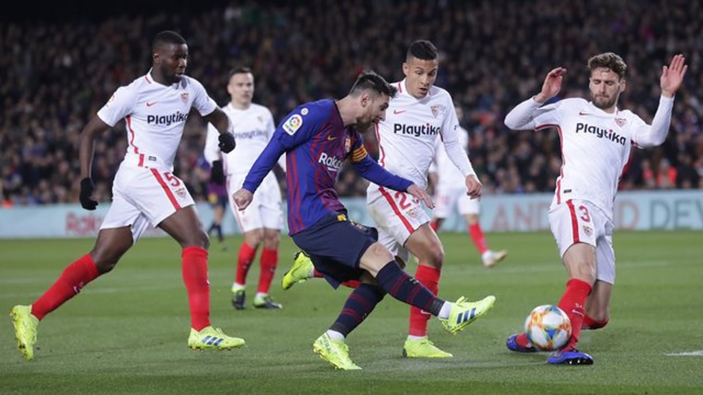 Bedrängt von gleich drei Gegenspielern des FC Sevilla kommt Barcelonas Lionel Messi (M) zum Schuss.