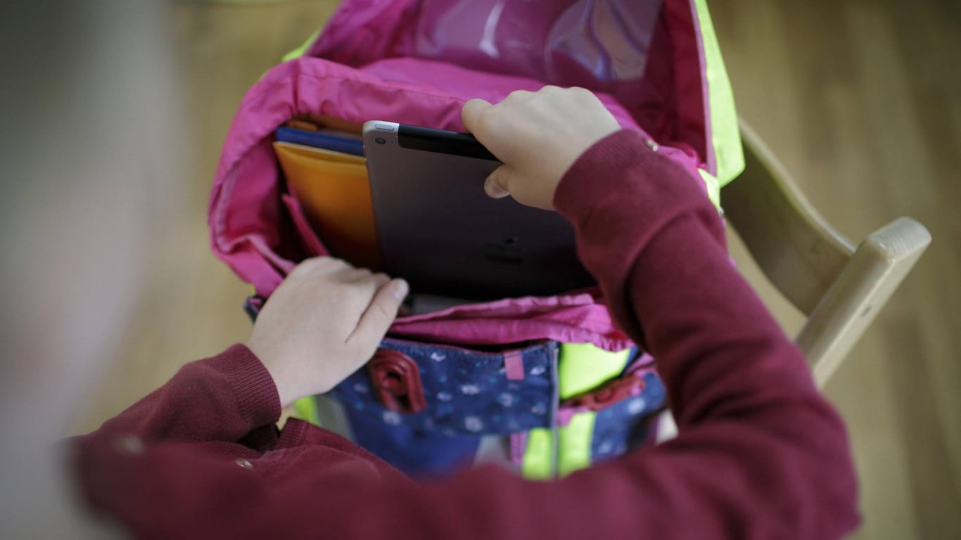 Ein Mädchen packt ein Tablet in ihren Schulranzen:: Bund und Länder streiten über den Digitalpakt.