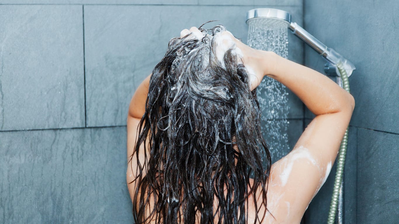 Frau bei der Haarwäsche: Haarspülungen werden nach dem Shampoo ins nasse Haar gegeben und einmassiert.