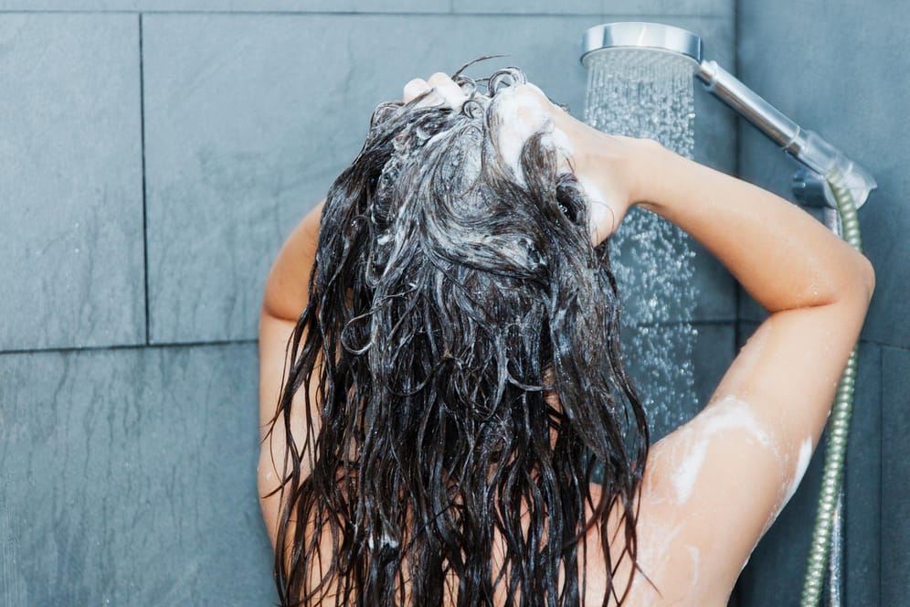 Frau bei der Haarwäsche: Haarspülungen werden nach dem Shampoo ins nasse Haar gegeben und einmassiert.