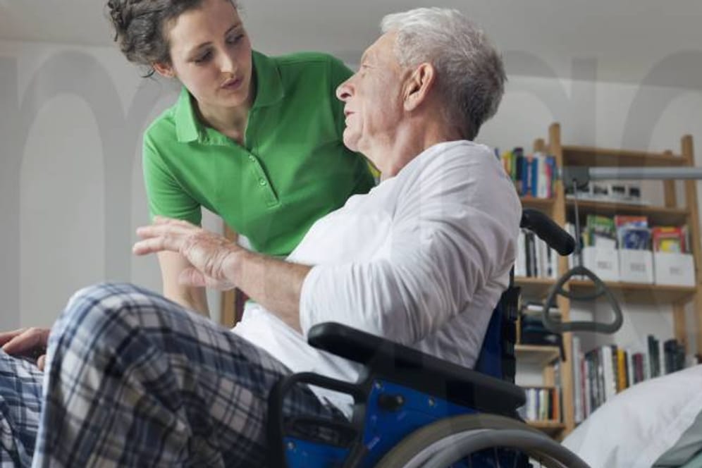 Älterer Mann im Rollstuhl mit Pflegerin