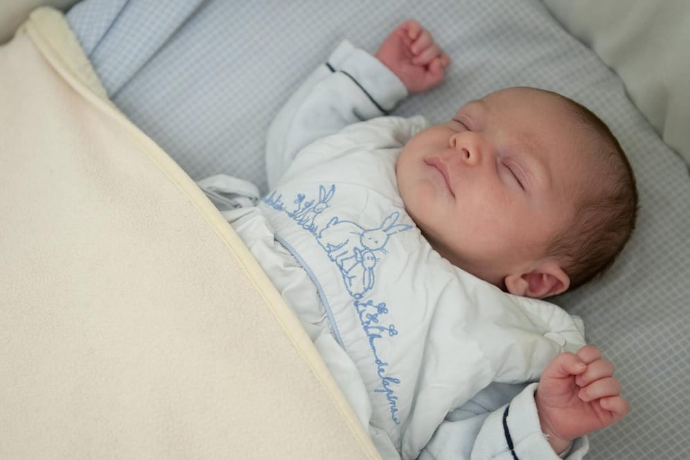 Schlafendes Baby: Der Halsausschnitt eines Babyschlafsacks darf nicht zu groß sein – der Babykopf könnte sonst durchrutschen.