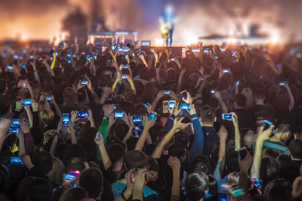 Konzert-Besucher filmen und fotografieren mit ihren Smartphones: Der Smartphone-Markt scheint langsam gesättigt. Doch weil die Geräte immer teurer werden, sprudeln trotzdem die Einnahmen der Hersteller.
