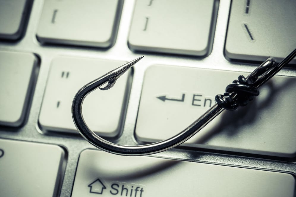 Ein Angelhaken auf einer Tastatur (Symbolbild): Mithilfe von Phishing-Mails versuchen Kriminelle, an Daten ihrer Opfer zu kommen.