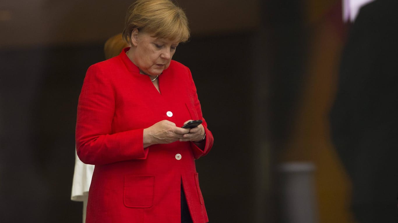 Angela Merkel tippt auf ihrem Smartphone: Die Bundeskanzlerin will dem chinesischen Mobilfunkausstatter Huawei strenger kontrollieren.