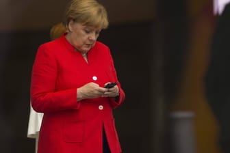 Angela Merkel tippt auf ihrem Smartphone: Die Bundeskanzlerin will dem chinesischen Mobilfunkausstatter Huawei strenger kontrollieren.