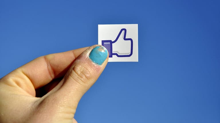 Eine Frauenhand hält einen "Gefällt mir"-Sticker hoch: Am Donnerstag will das Kartellamt seine Entscheidung verkünden, ob Facebooks Tracking-Methoden den Wettbewerb verzerren.