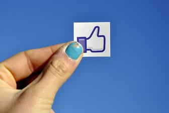 Eine Frauenhand hält einen "Gefällt mir"-Sticker hoch: Am Donnerstag will das Kartellamt seine Entscheidung verkünden, ob Facebooks Tracking-Methoden den Wettbewerb verzerren.