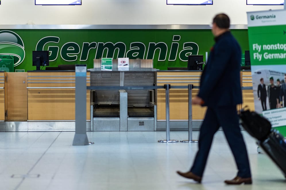 Ein Mann geht mit seinem Koffer am Flughafen Münster/Osnabrück an einem leeren Germania Schalter vorbei. Die Insolvenz der Airline führt am Dienstag auch an Flughäfen in Nordrhein-Westfalen zu Flugausfällen.