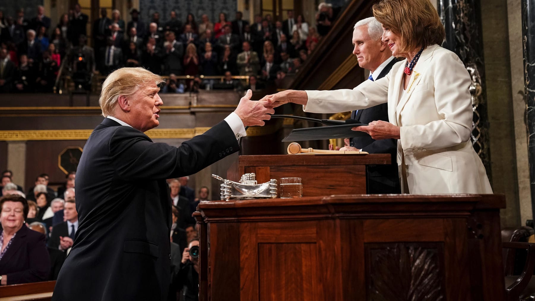 Donald Trump gibt vor seiner Rede zur Lage der Nation vor dem Kongress im Kapitol der Demokratin Nancy Pelosi, Vorsitzende des Abgeordnetenhauses, die Hand. Im Hintergrund steht Mike Pence, Vizepräsident der USA.