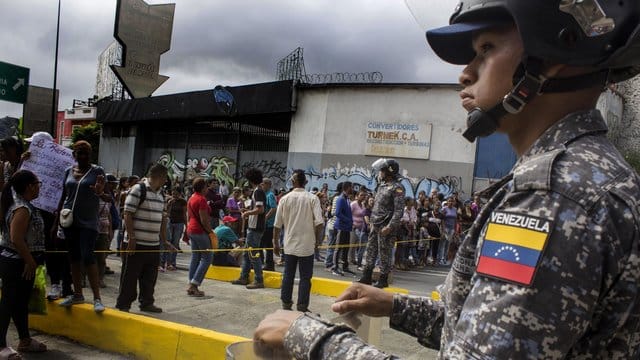 Ein Soldat beobachtet in einer Straße in Caracas Demonstranten.