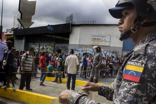 Ein Soldat beobachtet in einer Straße in Caracas Demonstranten.