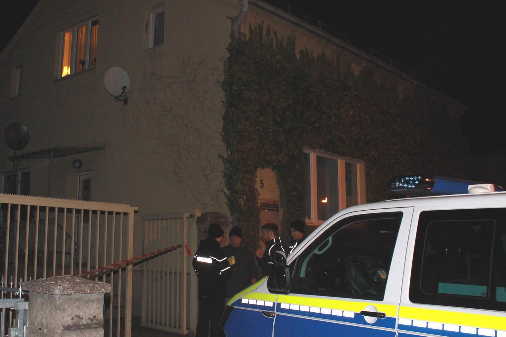 Polizeiauto und Polizisten stehen vor dem Grundstück, auf dem der Mann erschossen wurde: Die Tat passierte einem Polizeisprecher zufolge im Hinterhof des Hauses.