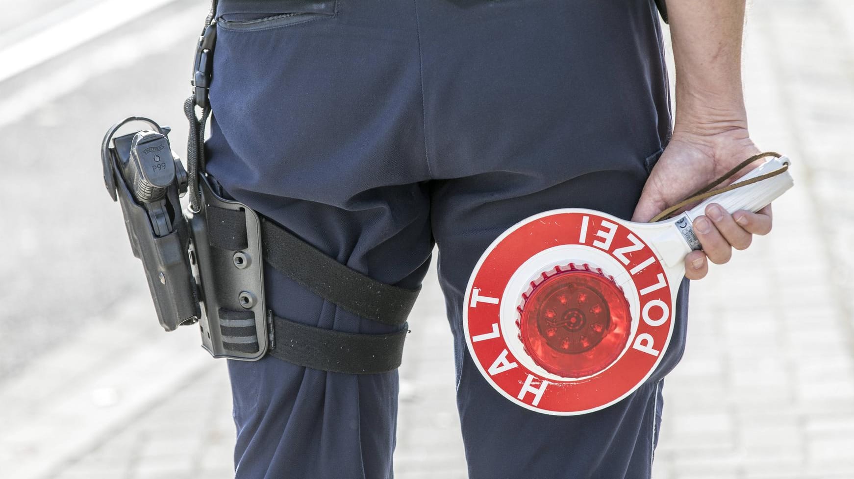 Polizist mit Warnweste und Anhaltekelle (Symbolbild): Die Fahrer müssen sich nun unter anderem wegen gefährlichen Eingriffs in den Straßenverkehr, Nötigung sowie diverser Verstöße nach dem Waffengesetz verantworten.