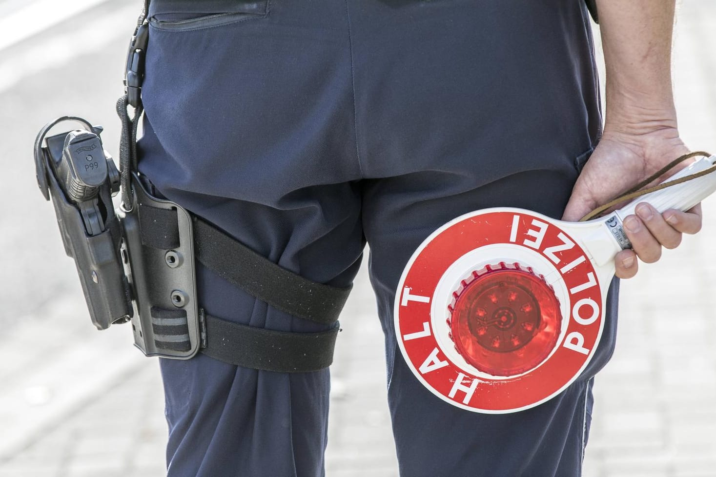 Polizist mit Warnweste und Anhaltekelle (Symbolbild): Die Fahrer müssen sich nun unter anderem wegen gefährlichen Eingriffs in den Straßenverkehr, Nötigung sowie diverser Verstöße nach dem Waffengesetz verantworten.
