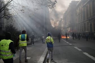 "Gelbwesten"-Demonstranten gehen auf eine brennende Barrikade zu.