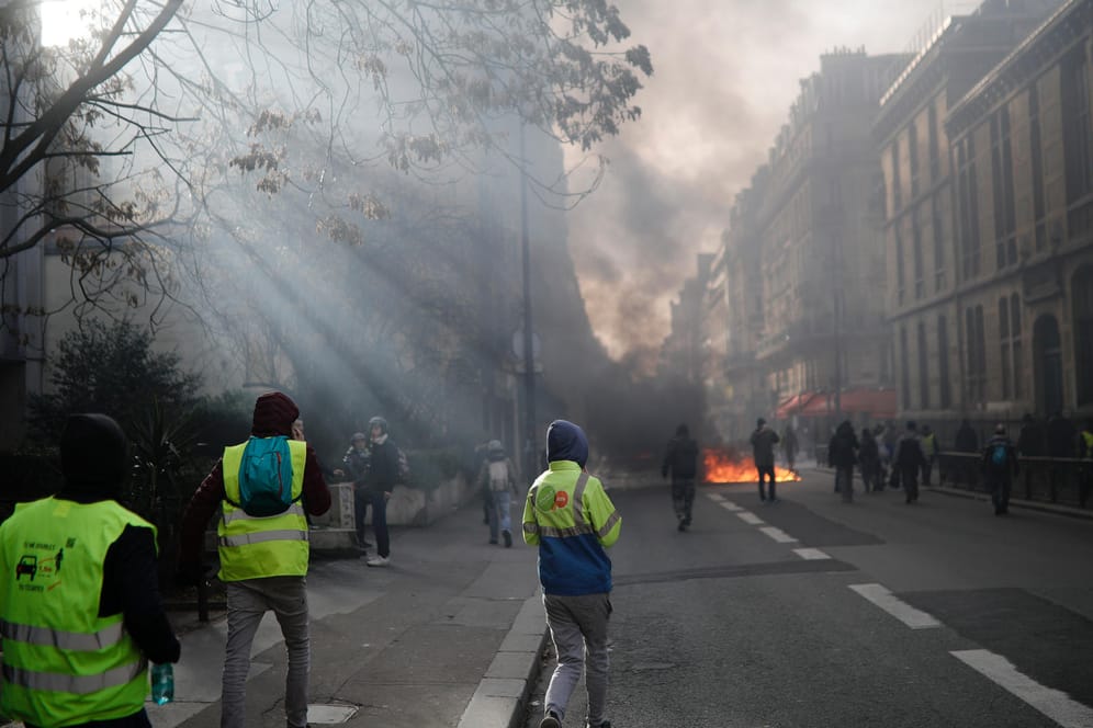 "Gelbwesten"-Demonstranten gehen auf eine brennende Barrikade zu: Einige Aktivisten sollen in Paris versucht haben, Zäune am Eingang der Nationalversammlung – dem Unterhaus des französischen Parlaments – zu durchbrechen.