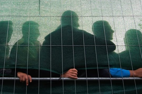 Flüchtlinge hinter dem Zaun einer Flüchtlingsunterkunft.