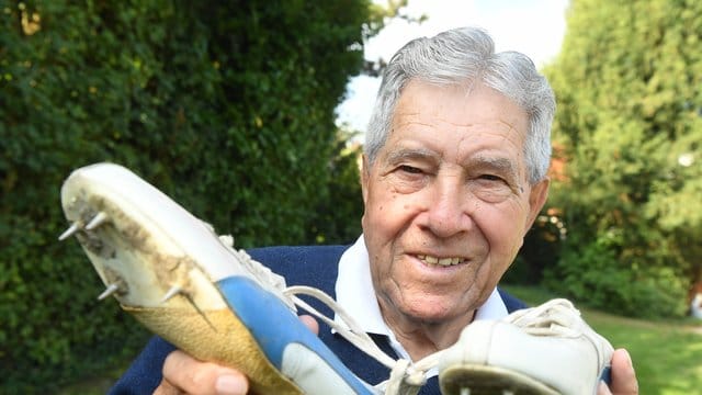 Heinz Fütterer posiert mit alten Laufschuhen aus dem Jahr 1957.