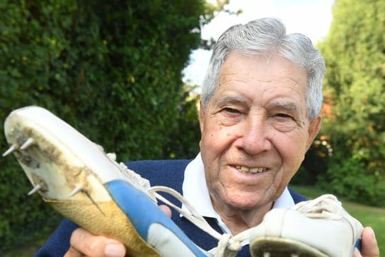 Heinz Fütterer posiert mit alten Laufschuhen aus dem Jahr 1957.