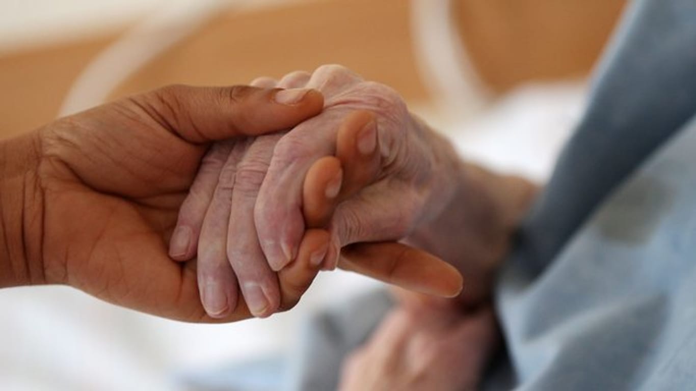 Eine Pflegerin hält die Hand einer älteren Frau: Der Bedarf an Betreuungskräften in Deutschland steigt rasant.