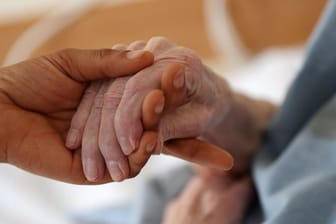 Eine Pflegerin hält die Hand einer älteren Frau: Der Bedarf an Betreuungskräften in Deutschland steigt rasant.